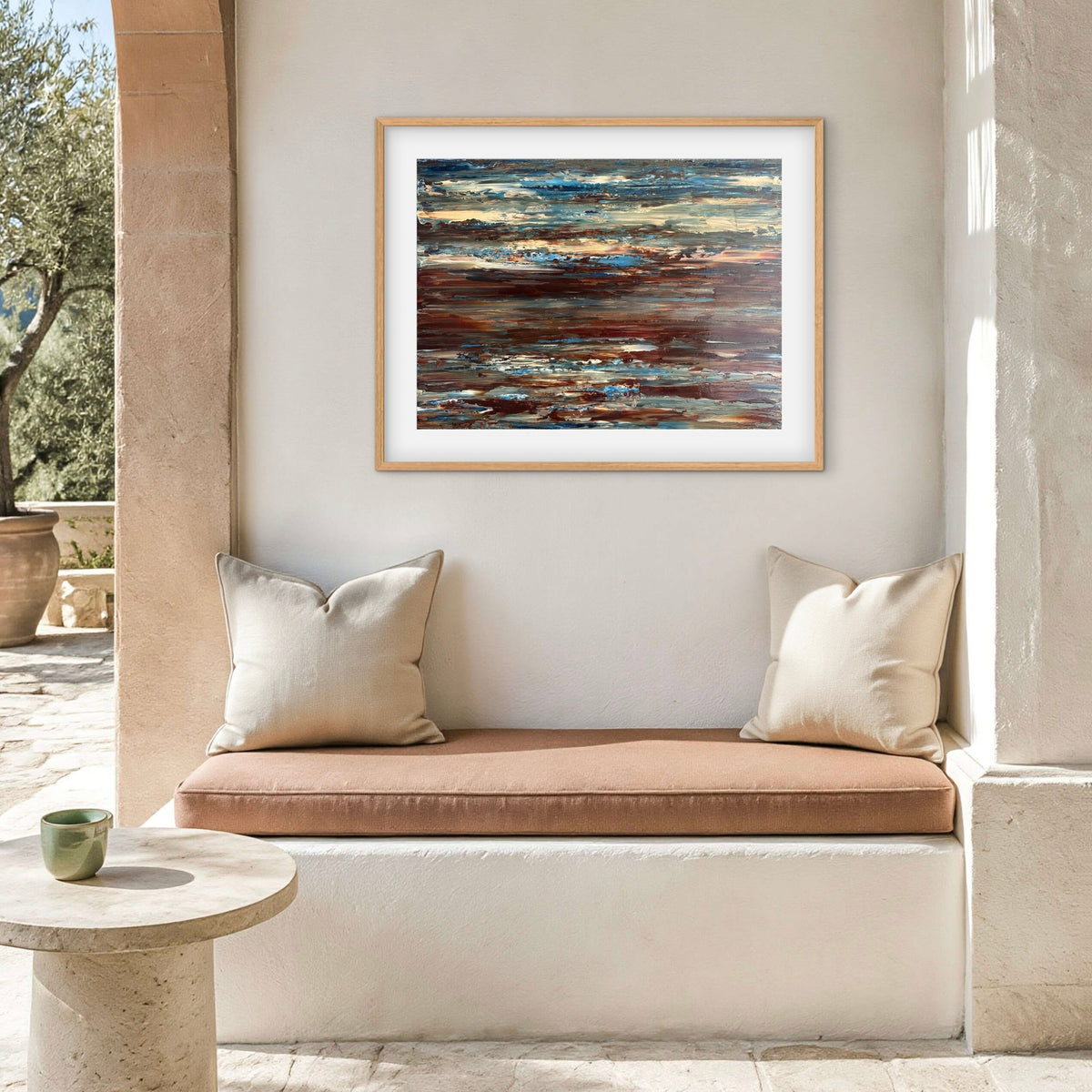 Coastal Drift framed print displayed above an outdoor patio nook with cushions