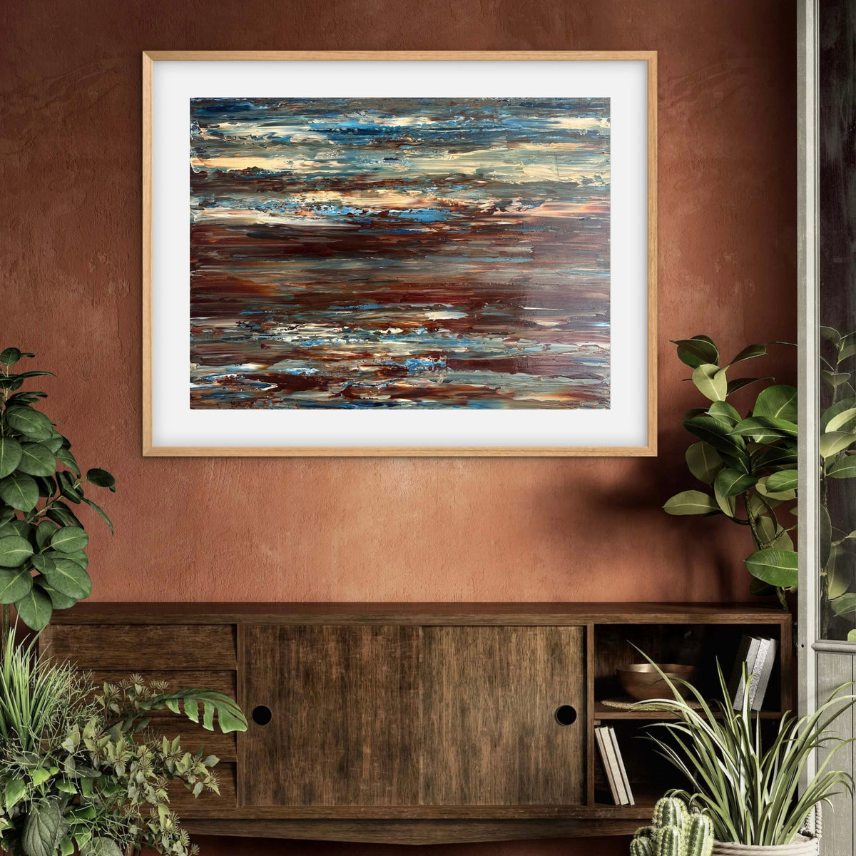 Coastal Drift framed print displayed above a wood sideboard against a terracotta wall