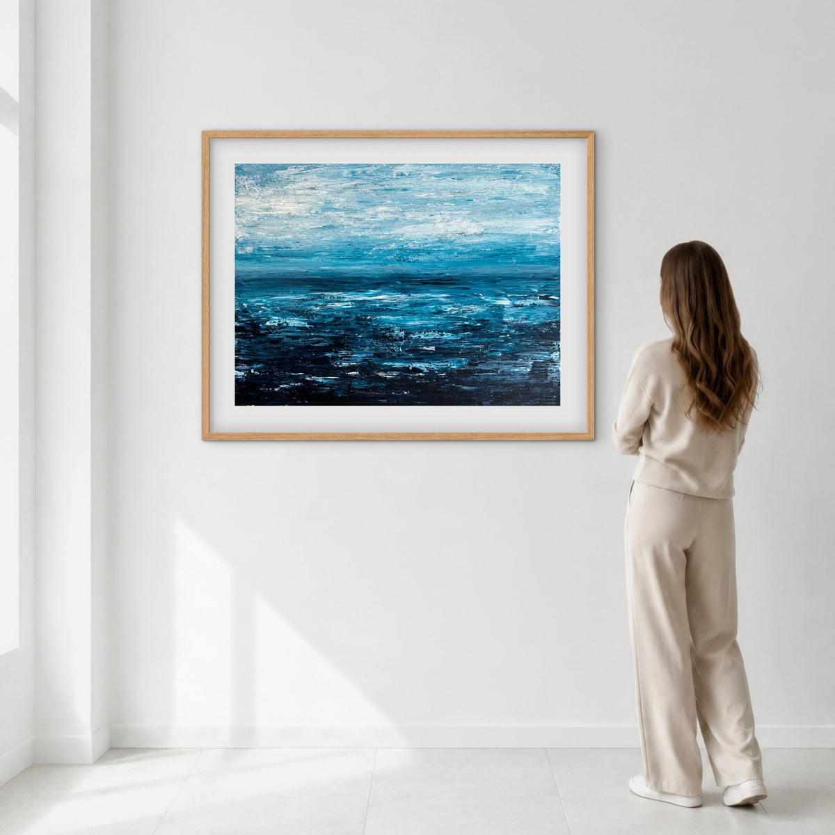 Quiet Tide framed print displayed on a wall as a woman views it, showing scale
